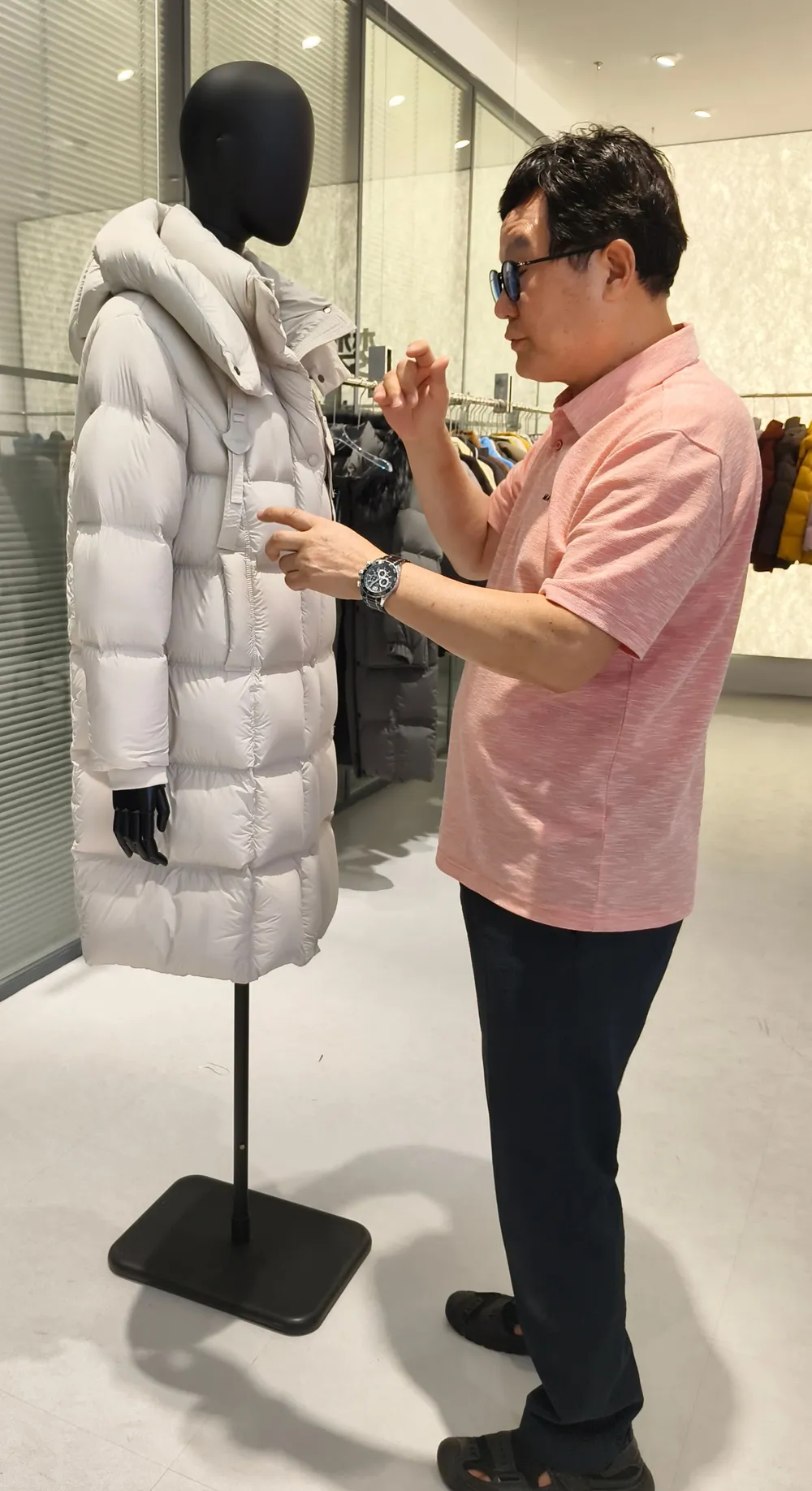 롱 패딩의 봉제선과 마감 상태를 손으로 짚어 확인하는 모습